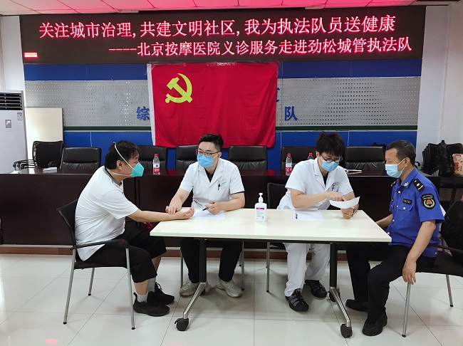 图为义诊现场医生为执法队员检诊问诊